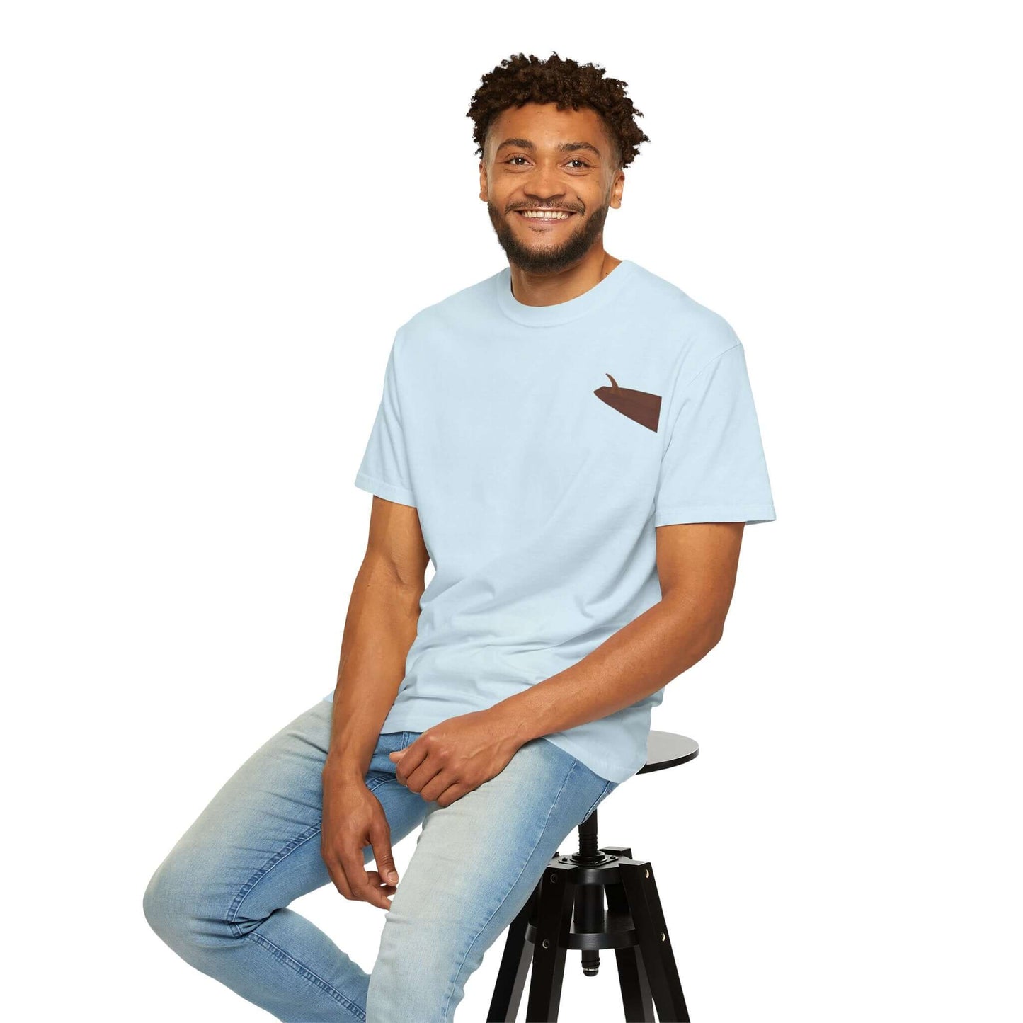 Smiling man wearing a light blue personalized t-shirt with a surf-inspired design, sitting on a stool.