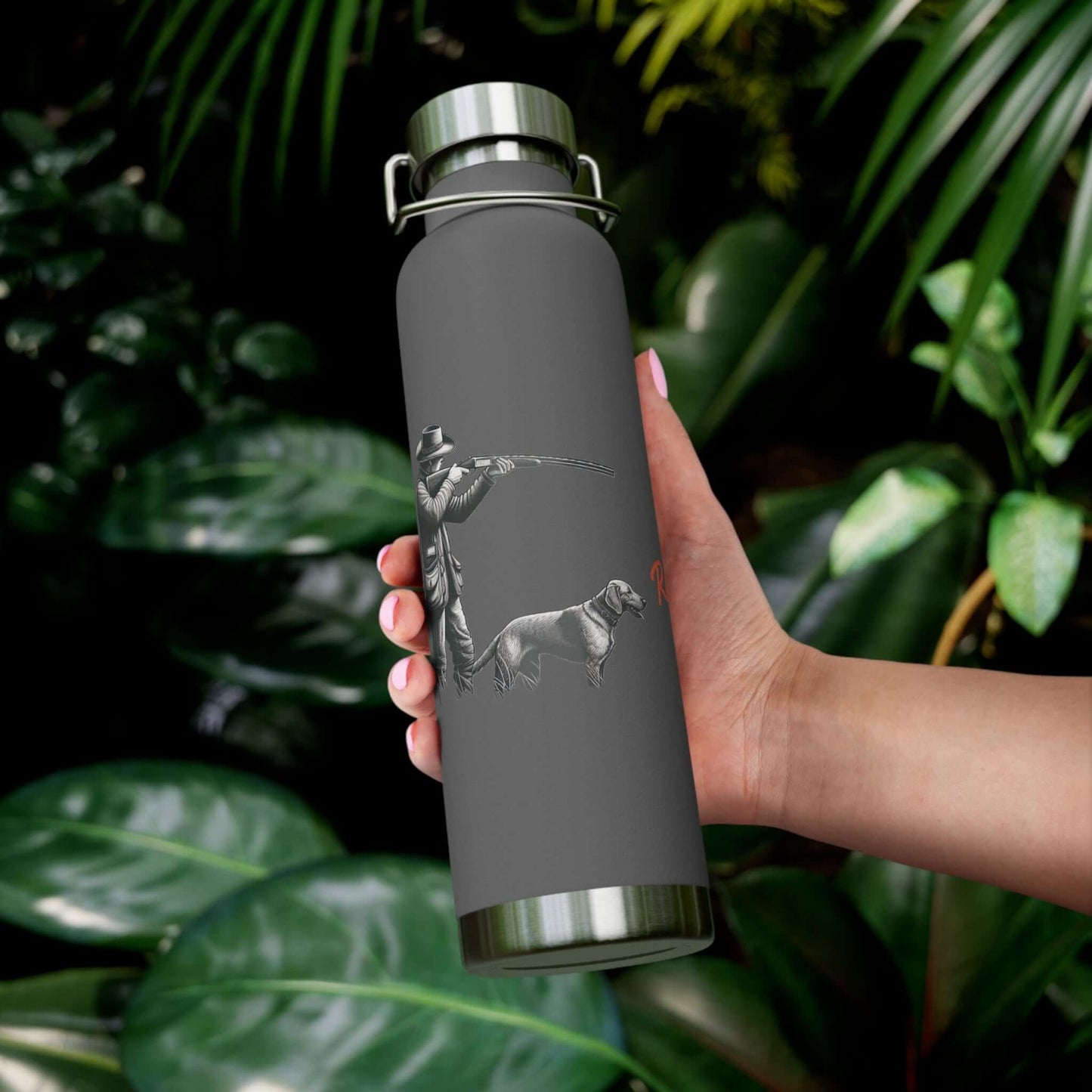 Hunter & Dog personalized vacuum insulated bottle held against lush green foliage
