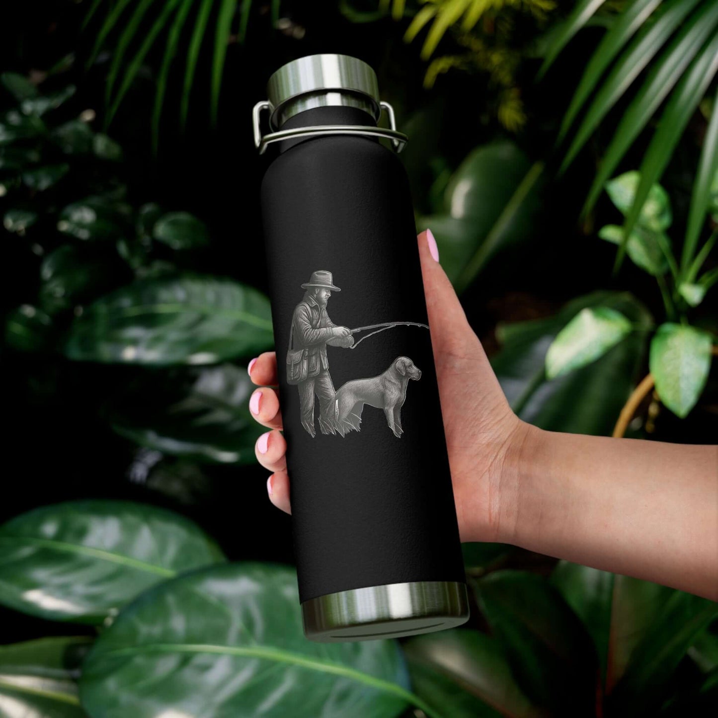 Hand holding a personalized copper insulated bottle with a fisherman and dog graphic against lush greenery.