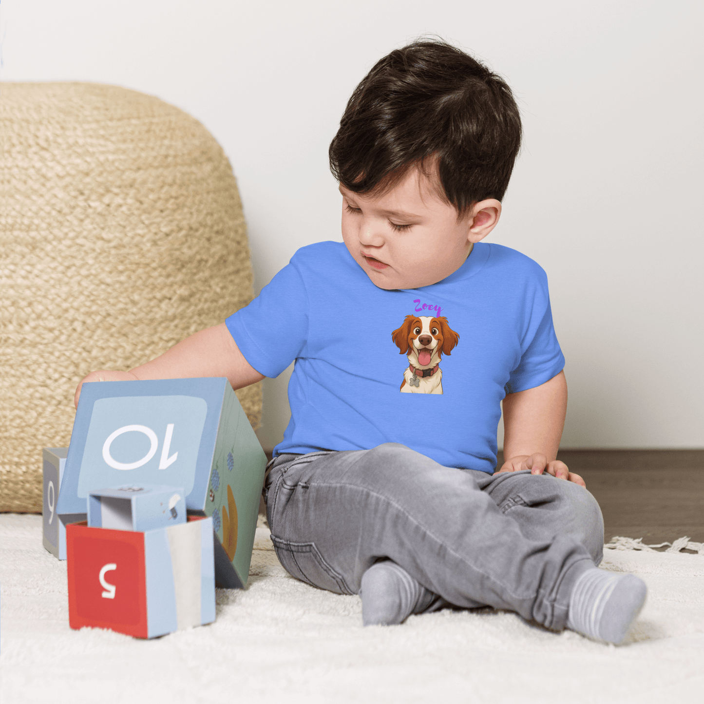 Baby wearing custom cartoon pet shirt, smiling while playing with colorful blocks on the floor.