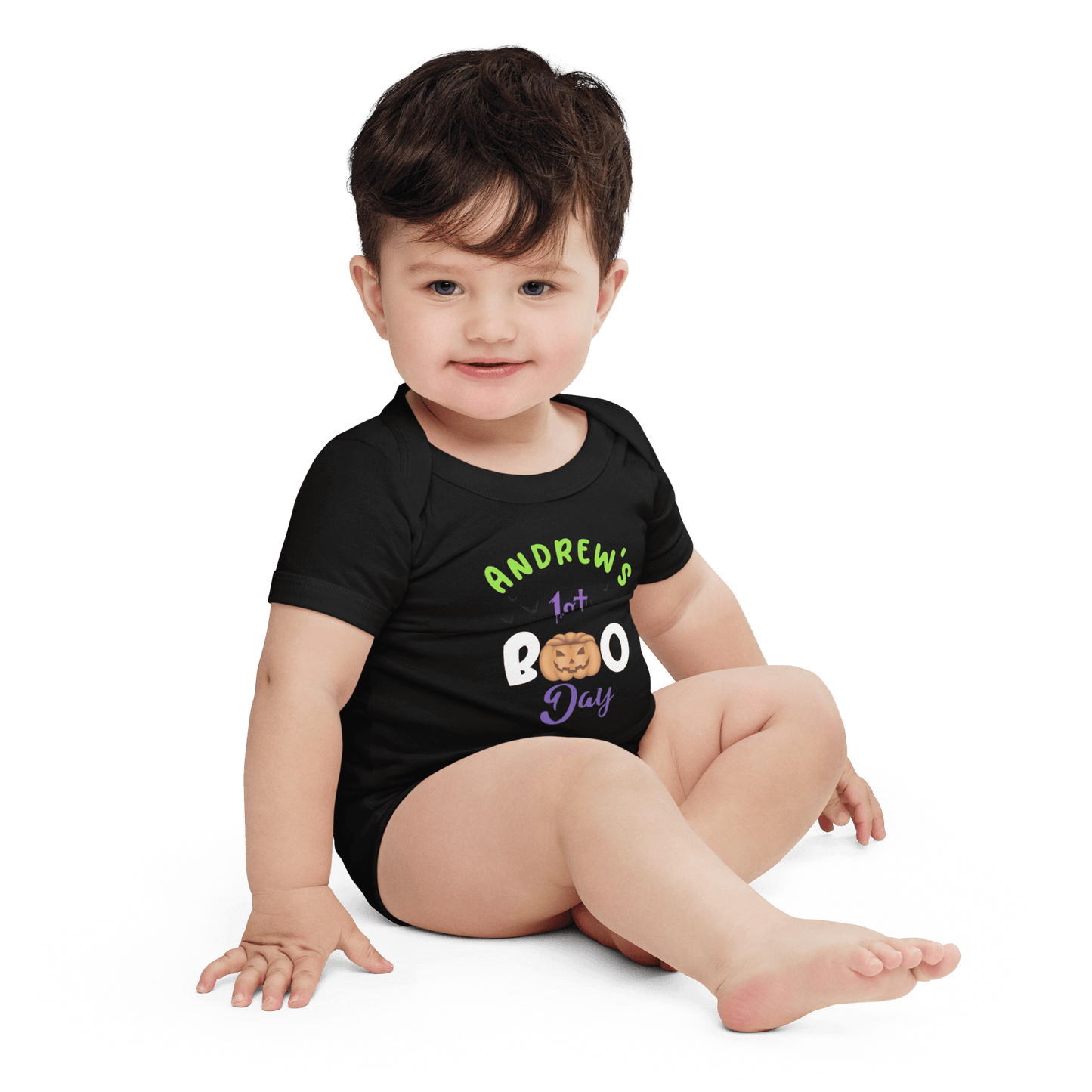 Baby wearing a personalized black Halloween bodysuit with 'Andrew's 1st Boo Day' text and playful pumpkin design.