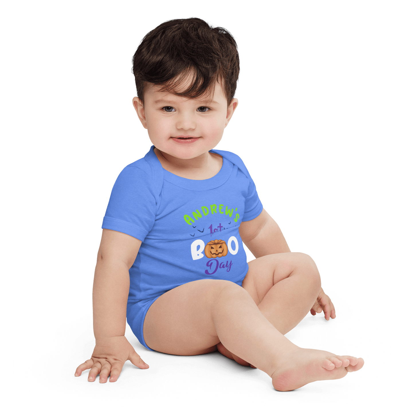 Baby in blue Halloween bodysuit with playful pumpkin design, celebrating 1st Boo Day.