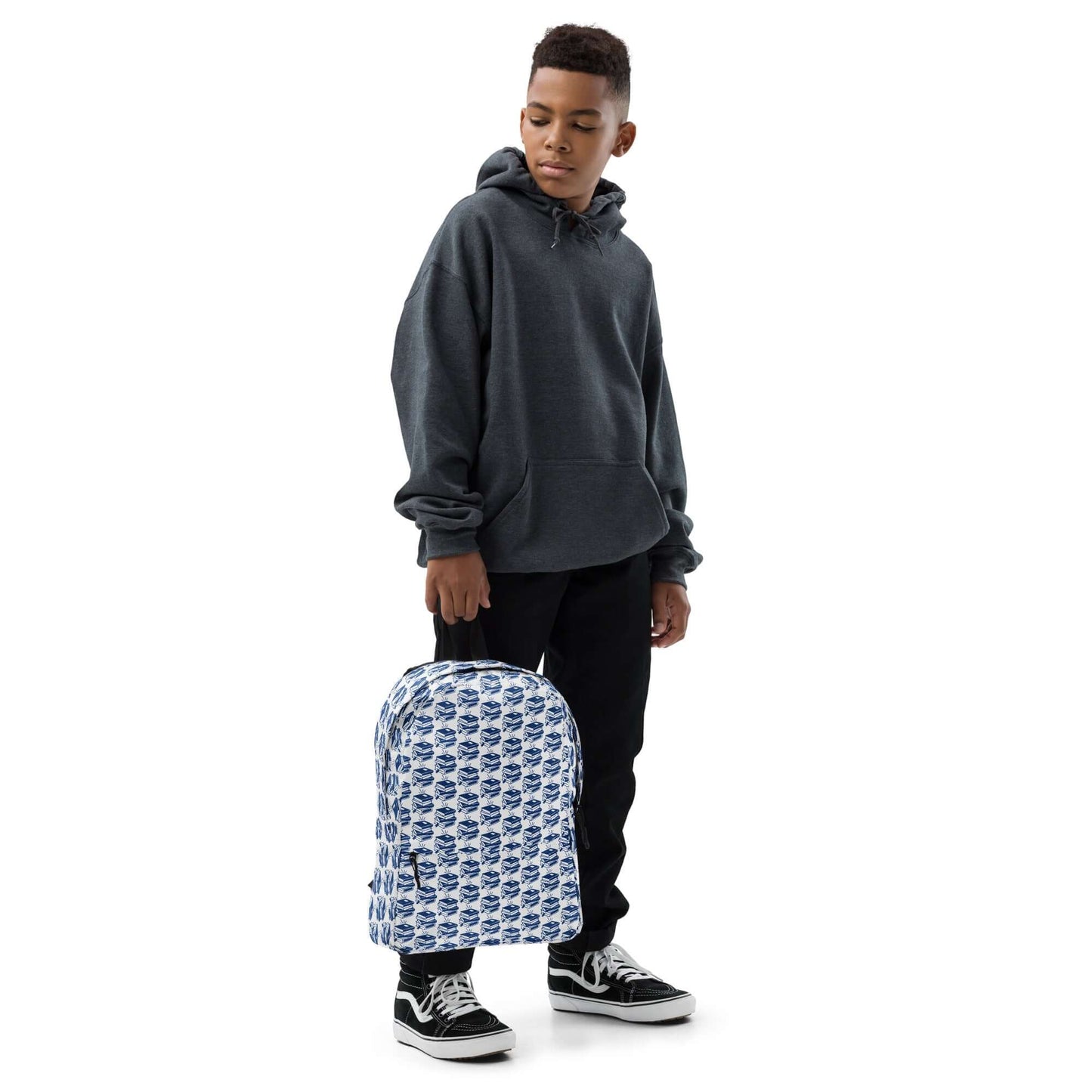 Young boy in a gray hoodie holding The Bookish Backpack with a geometric book pattern.
