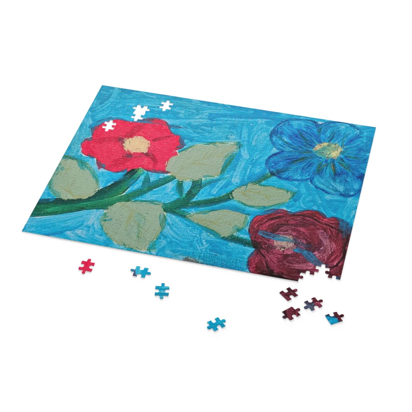 Colorful flower puzzle pieces scattered next to a vibrant blue floral puzzle awaiting completion.
