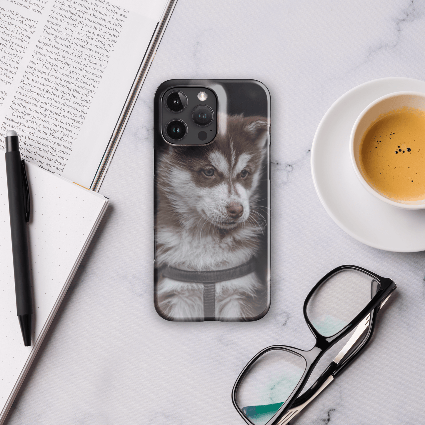 Custom iPhone case featuring a cute, fluffy puppy design on a stylish desk with coffee and glasses.