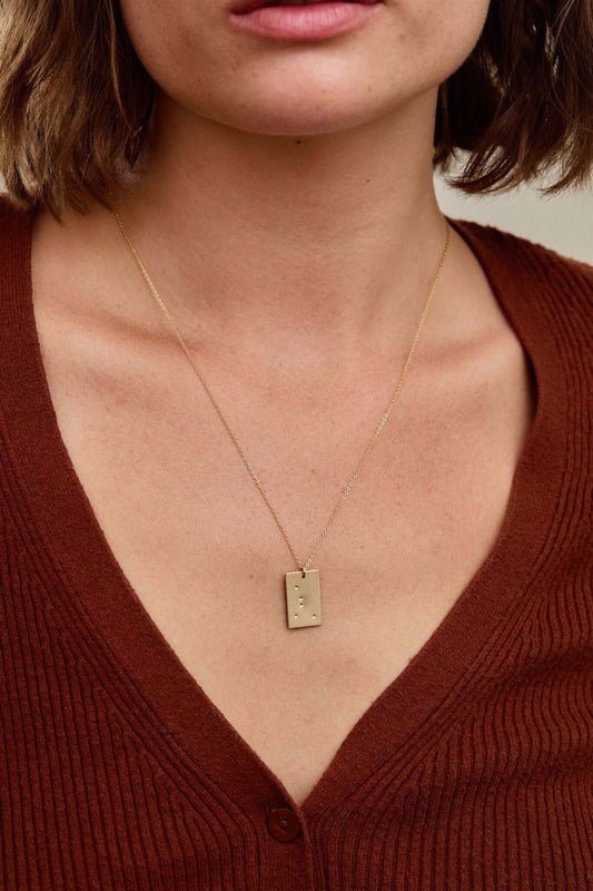 Goldie Constellation Necklace | Hand-Stamped Zodiac Pendant in 14k Gold-Filled worn by a woman.