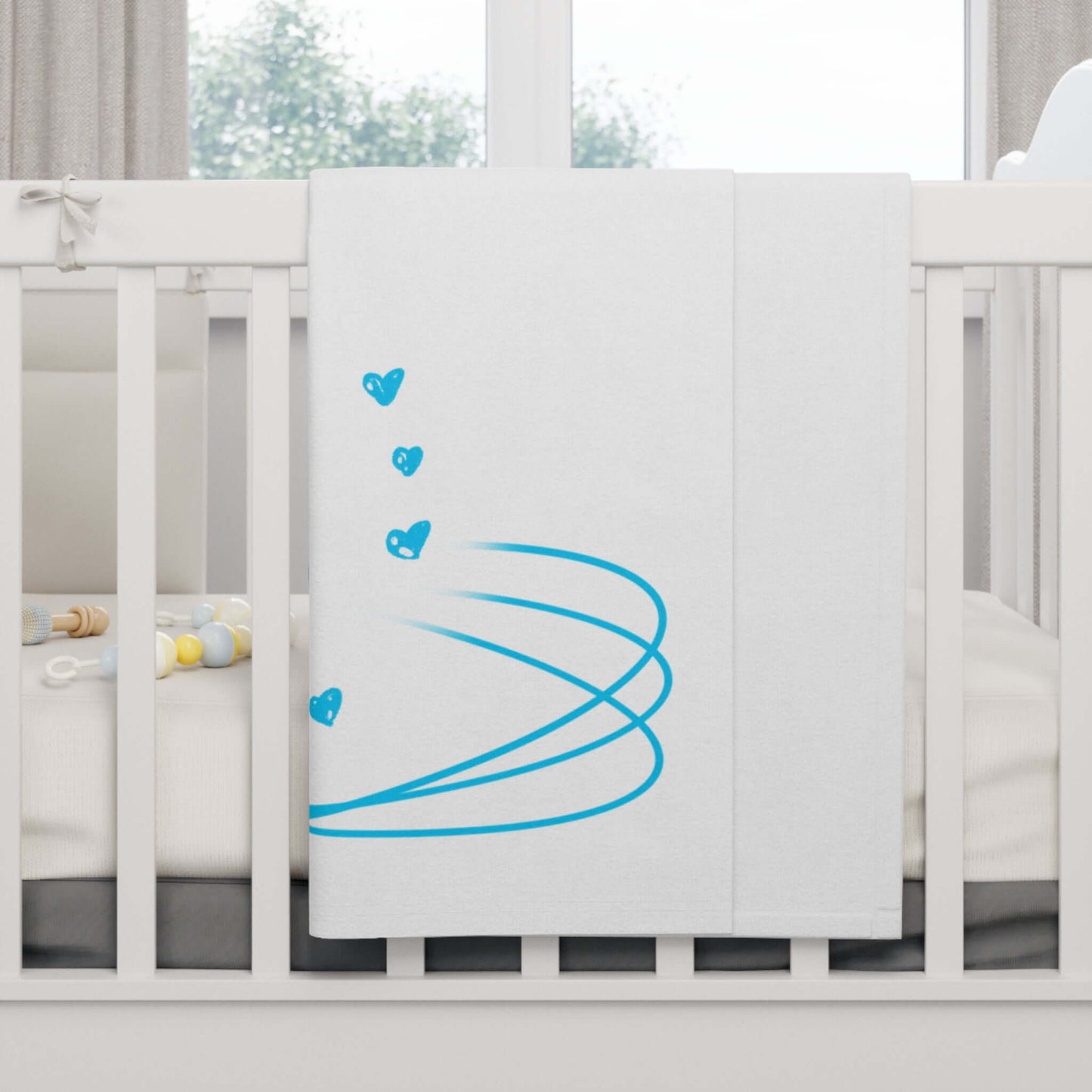 Personalized baby blanket with blue heart design draped over a crib for cozy nursery decor.
