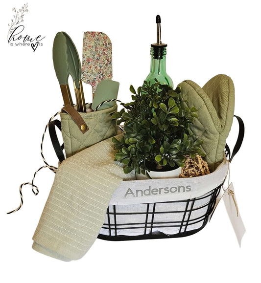 Personalized Home Warming Gift Basket with Engraved Cutting Board featuring kitchen utensils and a potted plant.