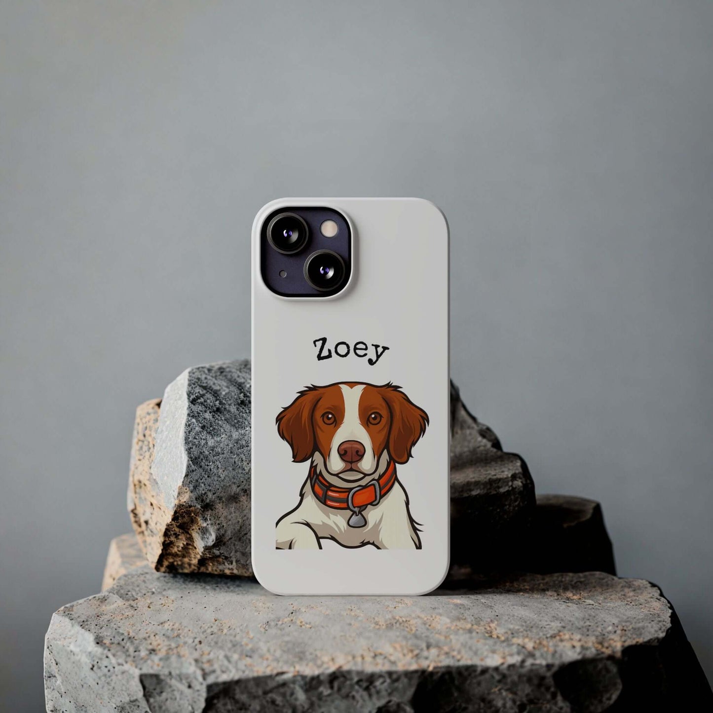 Custom cartoon phone case featuring a dog illustration named Zoey, on a rocky background.