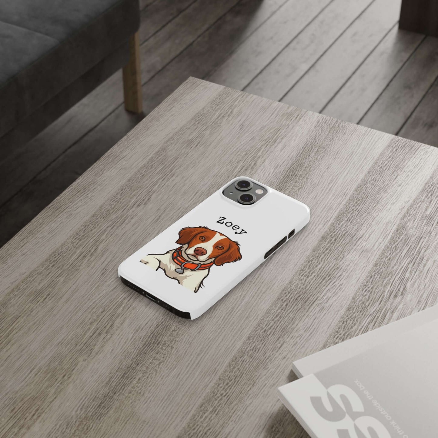 Custom cartoon dog phone case featuring a dog portrait with the name Zoey, resting on a wooden table.