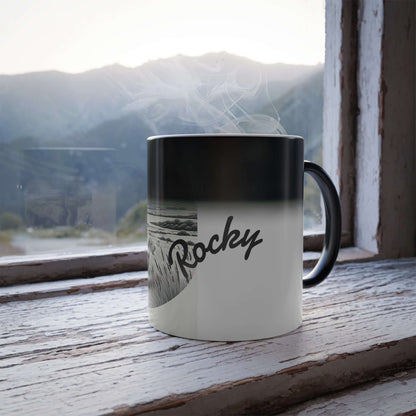 Personalized vintage heat-reactive coffee mug with 'Rocky' design, placed on a rustic window sill with mountains view.