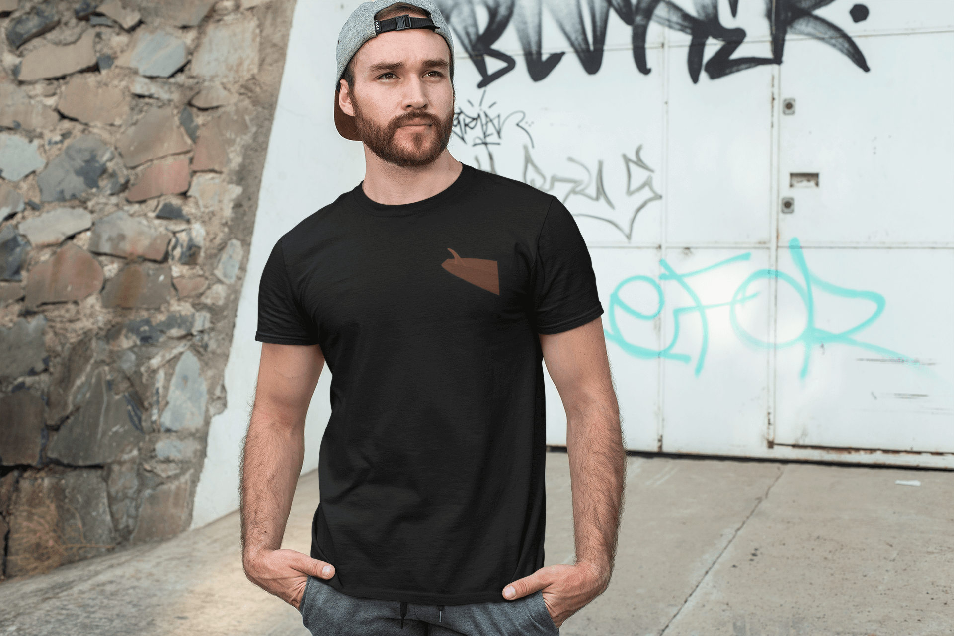 Man wearing a black personalized surf-inspired t-shirt with a cap in an urban setting.