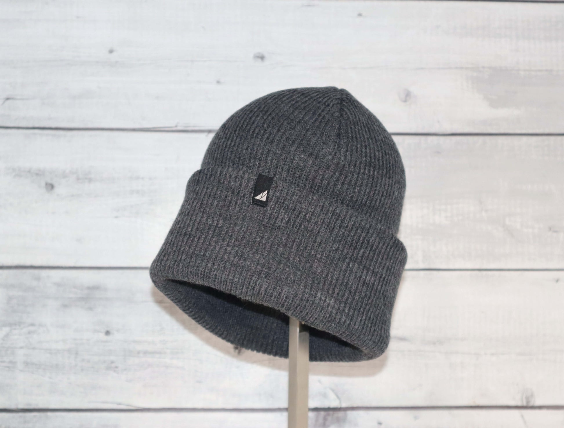 Adult Acrylic Cuff Hat – Soft Knit Beanie in gray color against a wooden background, ideal for warmth and comfort.