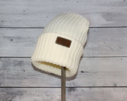 Adult Acrylic Ribbed Cuff Hat – Classic Warmth with Purpose displayed on a stand in soft white color with a textured knit design.
