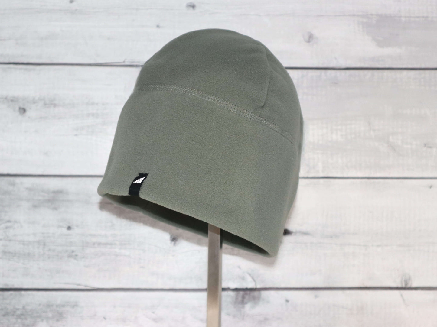 Adult Fleece Cap – Warm Stretch Beanie displayed on a holder against a wooden background.