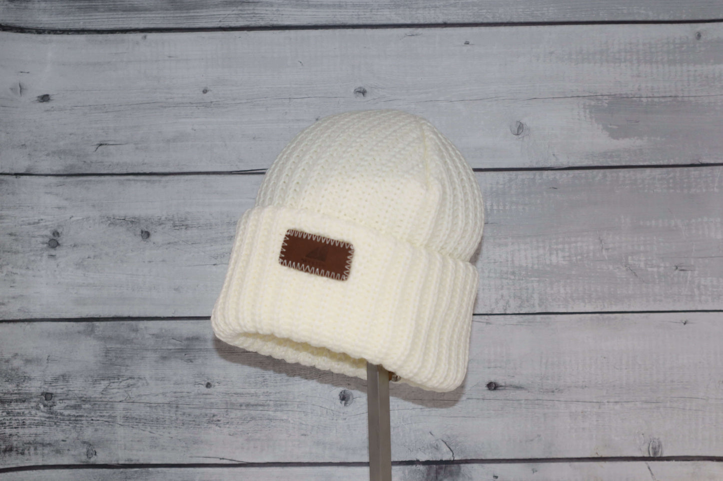 Child Acrylic Ribbed Cuff Hat – Soft, Stretchy & Purposeful displayed on a mannequin against a rustic wood background.