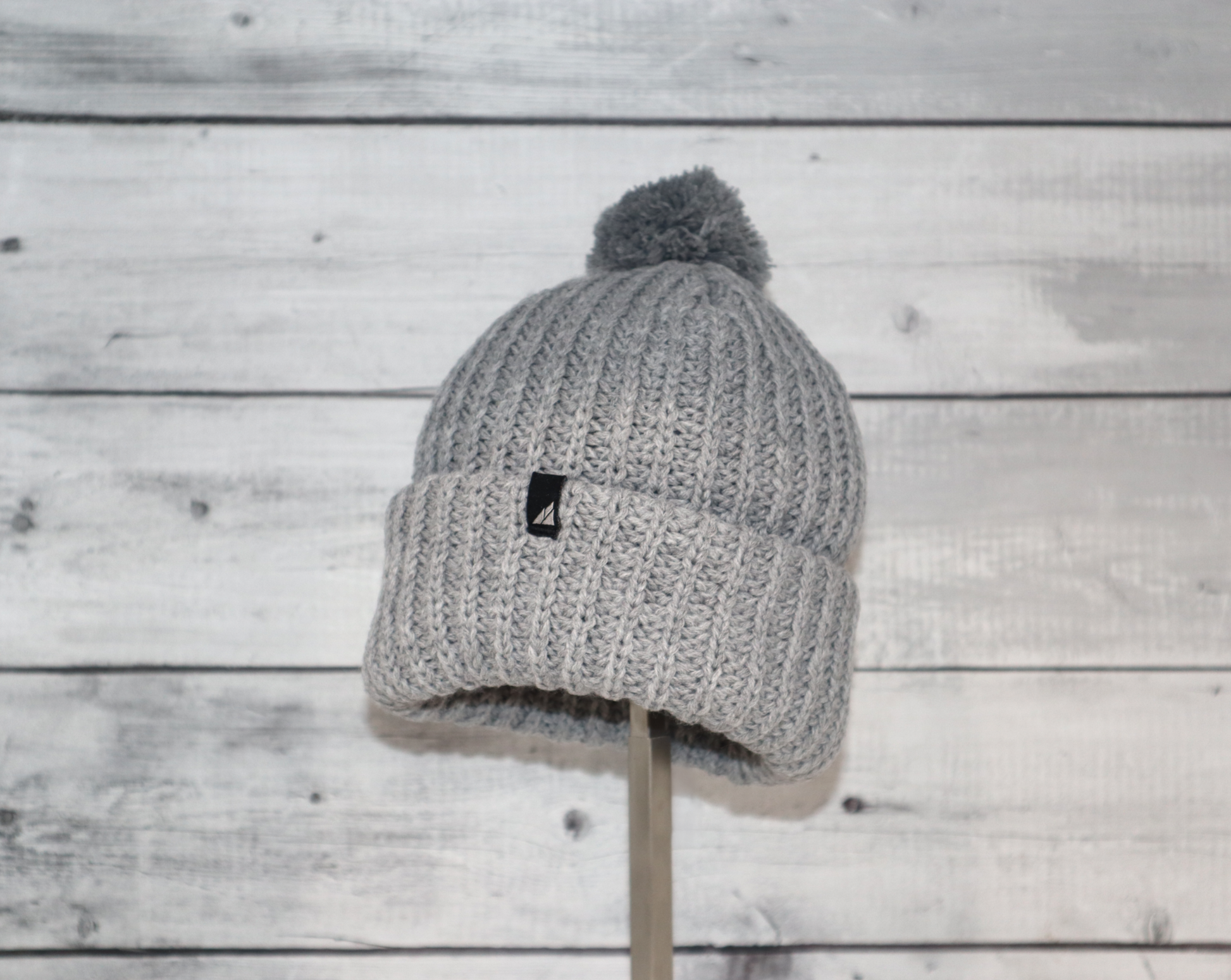 Child Acrylic Ribbed Cuff Hat with Pom – Cozy, Playful, Purposeful on wooden background.