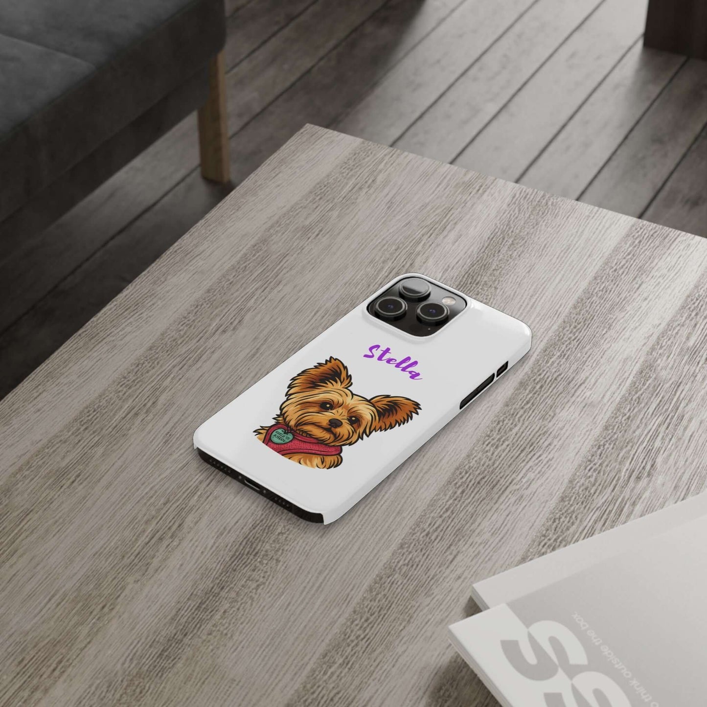 Custom dog cartoon phone case with a Yorkie design and name Stella, placed on a wooden table.