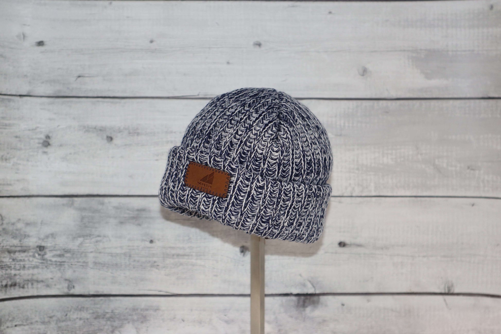 Infant Acrylic Ribbed Cuff Hat – Soft, Stretchy & Purposeful in navy with leather tag showcased on a wooden stand.