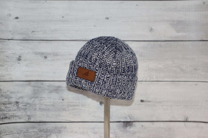 Infant Acrylic Ribbed Cuff Hat – Soft, Stretchy & Purposeful in navy with leather tag showcased on a wooden stand.