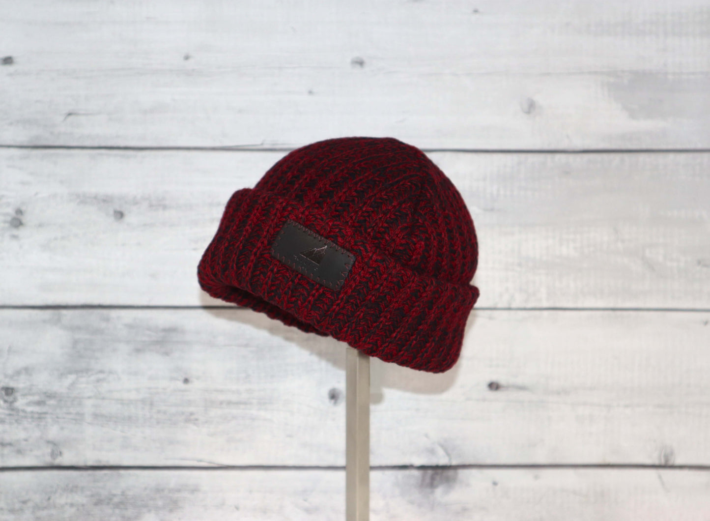 Infant Acrylic Ribbed Cuff Hat – Soft, Stretchy & Purposeful displayed on a stand against a wooden background.