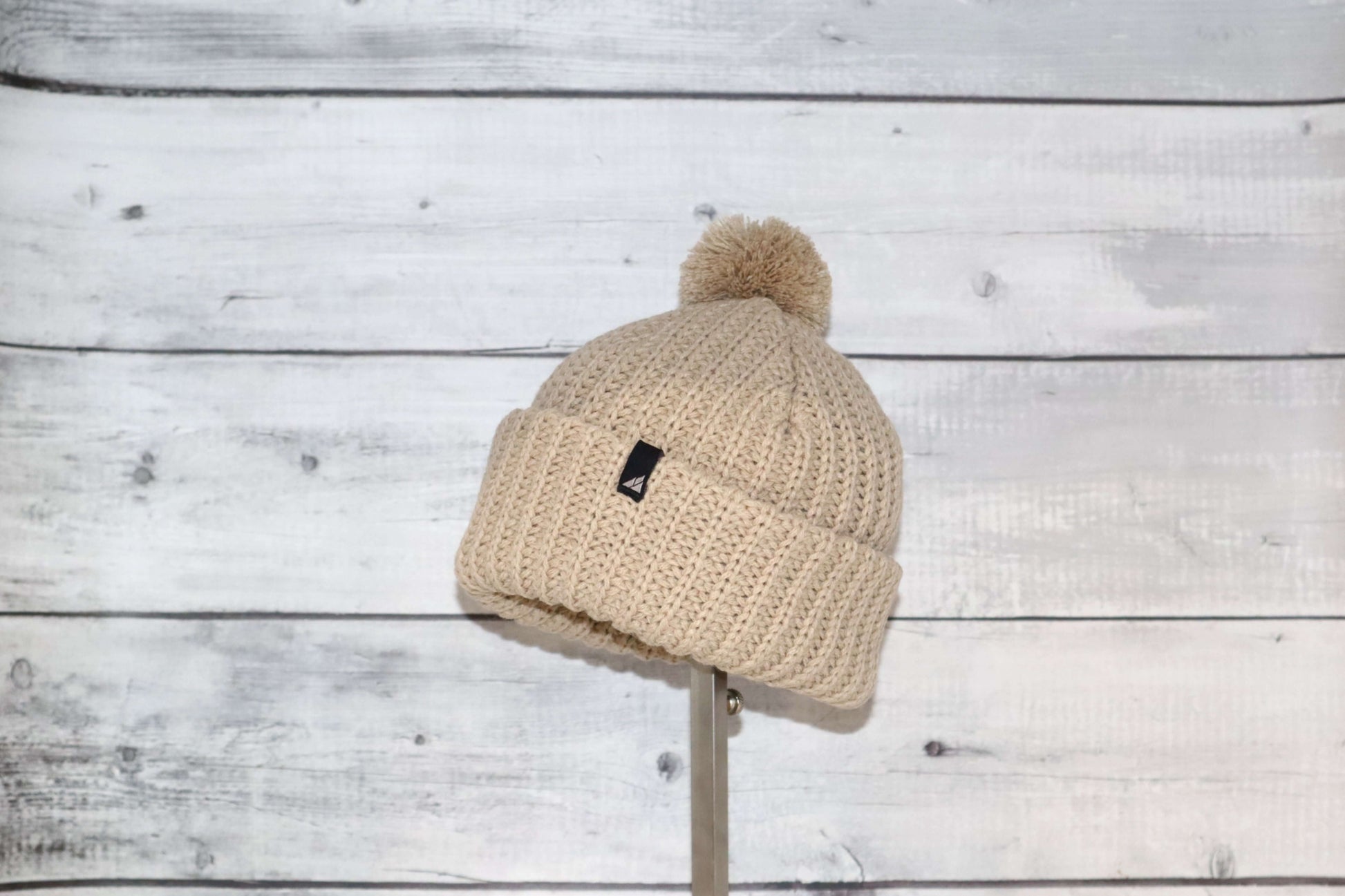 Toddler Acrylic Ribbed Cuff with Pom Hat – Cozy & Purposeful displayed against a rustic wooden background.
