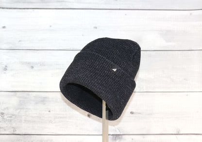 Adult Acrylic Cuff Hat – Soft Knit Beanie in dark color on display against a rustic wooden background.