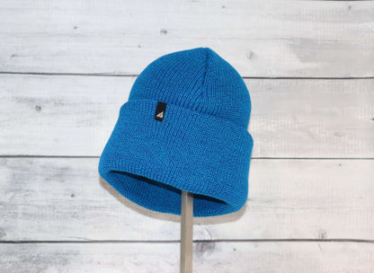Adult Acrylic Cuff Hat – Soft Knit Beanie in vibrant blue color displayed on a stand against a wooden background.