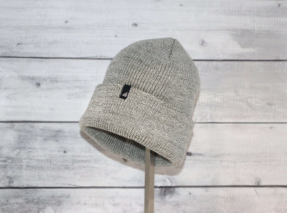 Adult Acrylic Cuff Hat – Soft Knit Beanie displayed on a stand against a wooden background.
