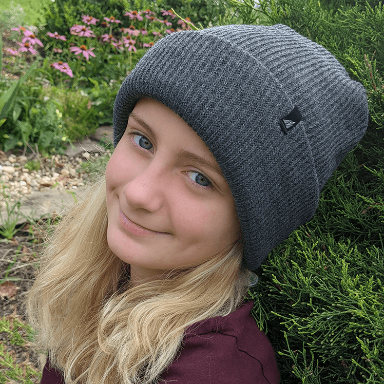 Adult Acrylic Cuff Hat – Soft Knit Beanie worn by a smiling girl in a garden setting.