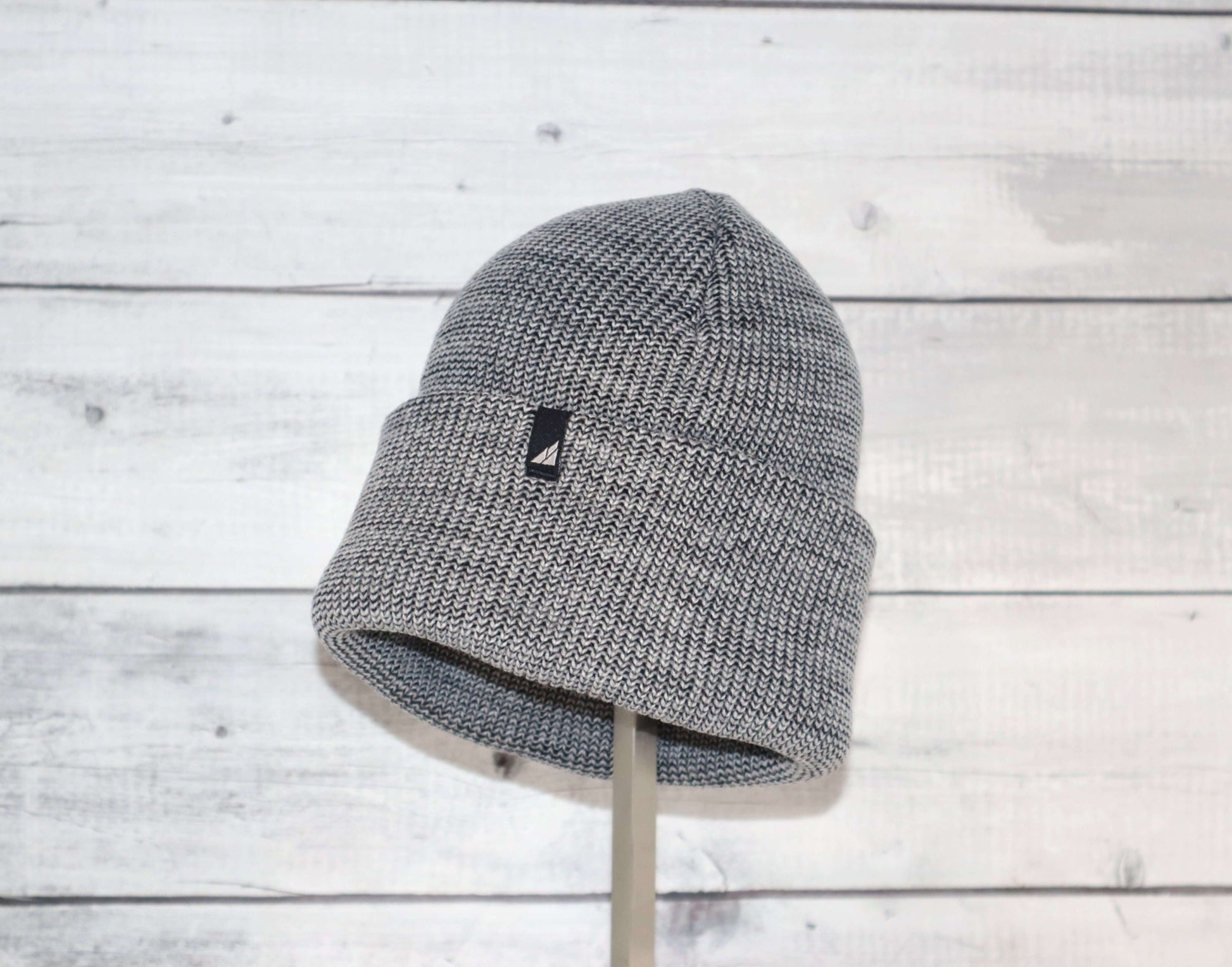 Adult Acrylic Cuff Hat – Soft Knit Beanie displayed on a stand against a rustic wooden background