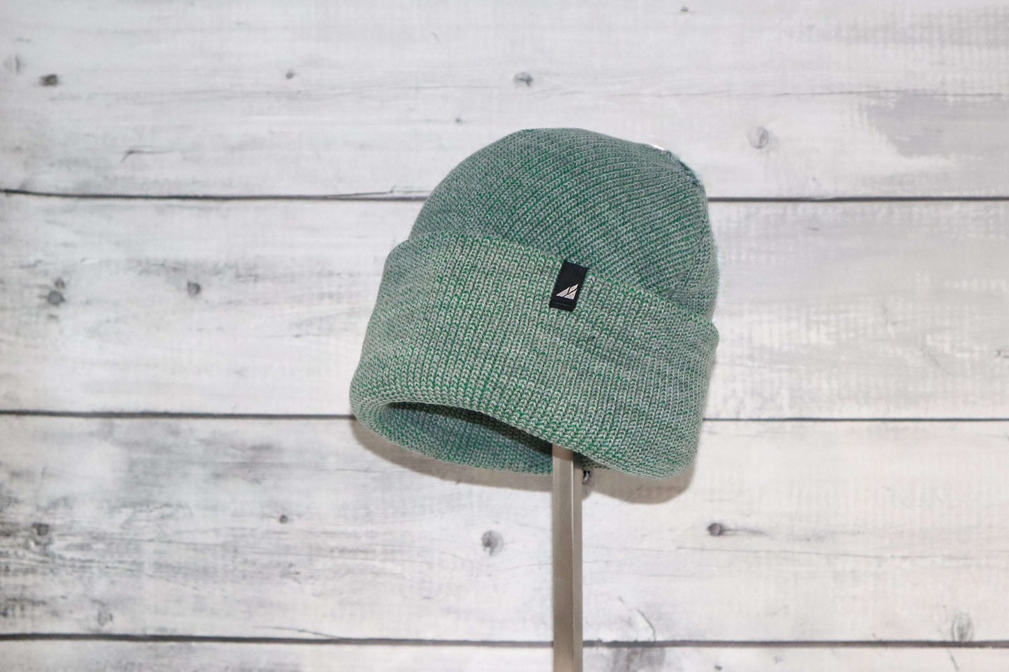 Adult Acrylic Cuff Hat – Soft Knit Beanie shown in green on display against a rustic wooden background.