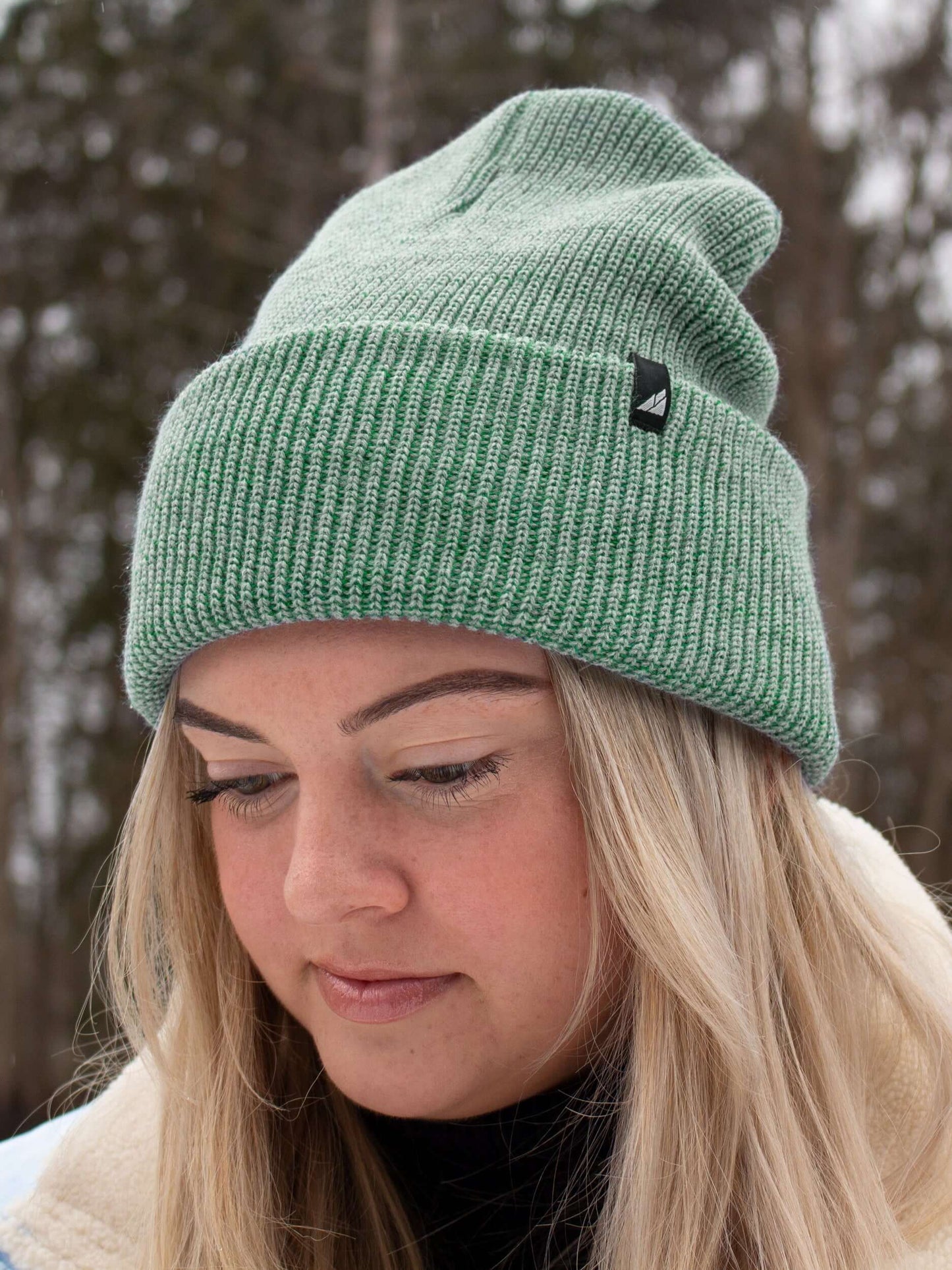Adult Acrylic Cuff Hat – Soft Knit Beanie worn by a woman in a winter setting, featuring a green ribbed knit design.