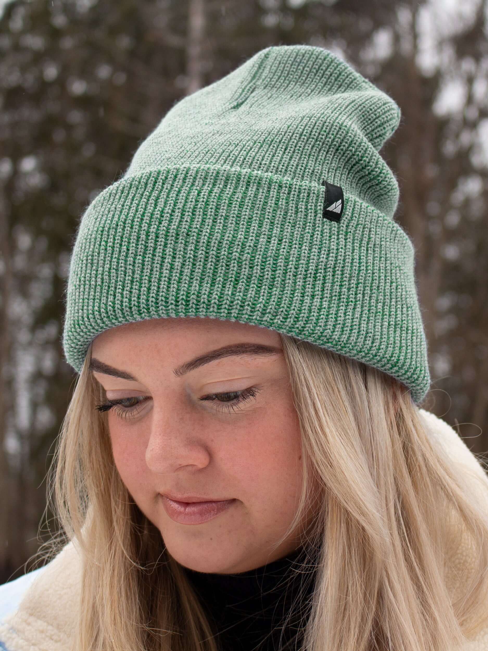 Adult Acrylic Cuff Hat – Soft Knit Beanie worn by a woman in a winter setting, featuring a green ribbed knit design.
