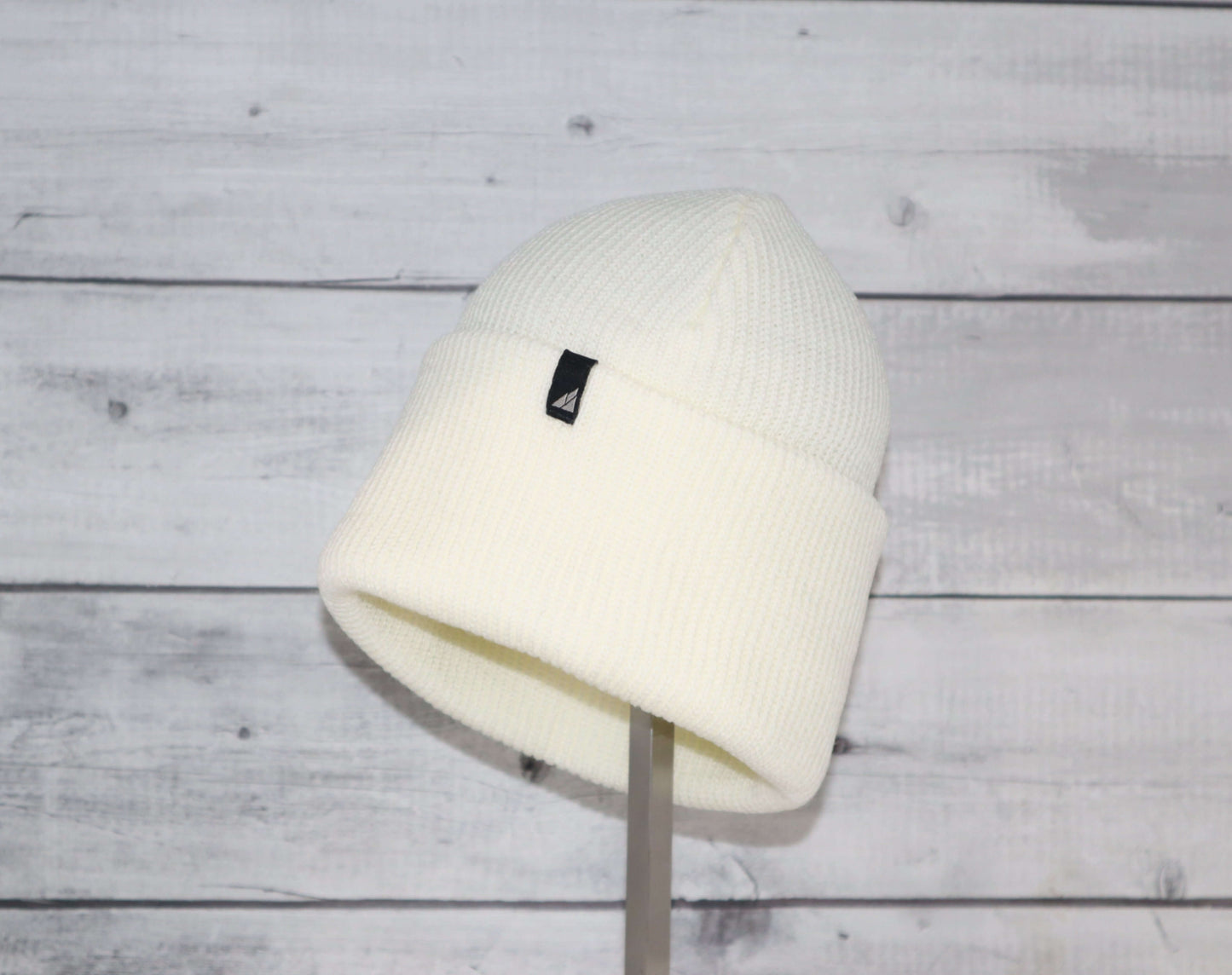 Adult Acrylic Cuff Hat – Soft Knit Beanie displayed on a stand against a wooden background.