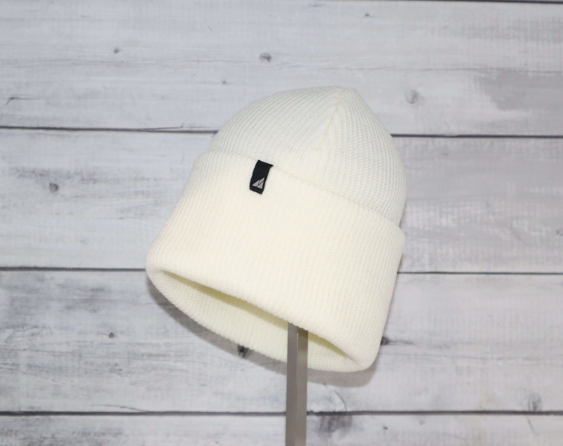 Adult Acrylic Cuff Hat – Soft Knit Beanie displayed on a stand against a wooden background.