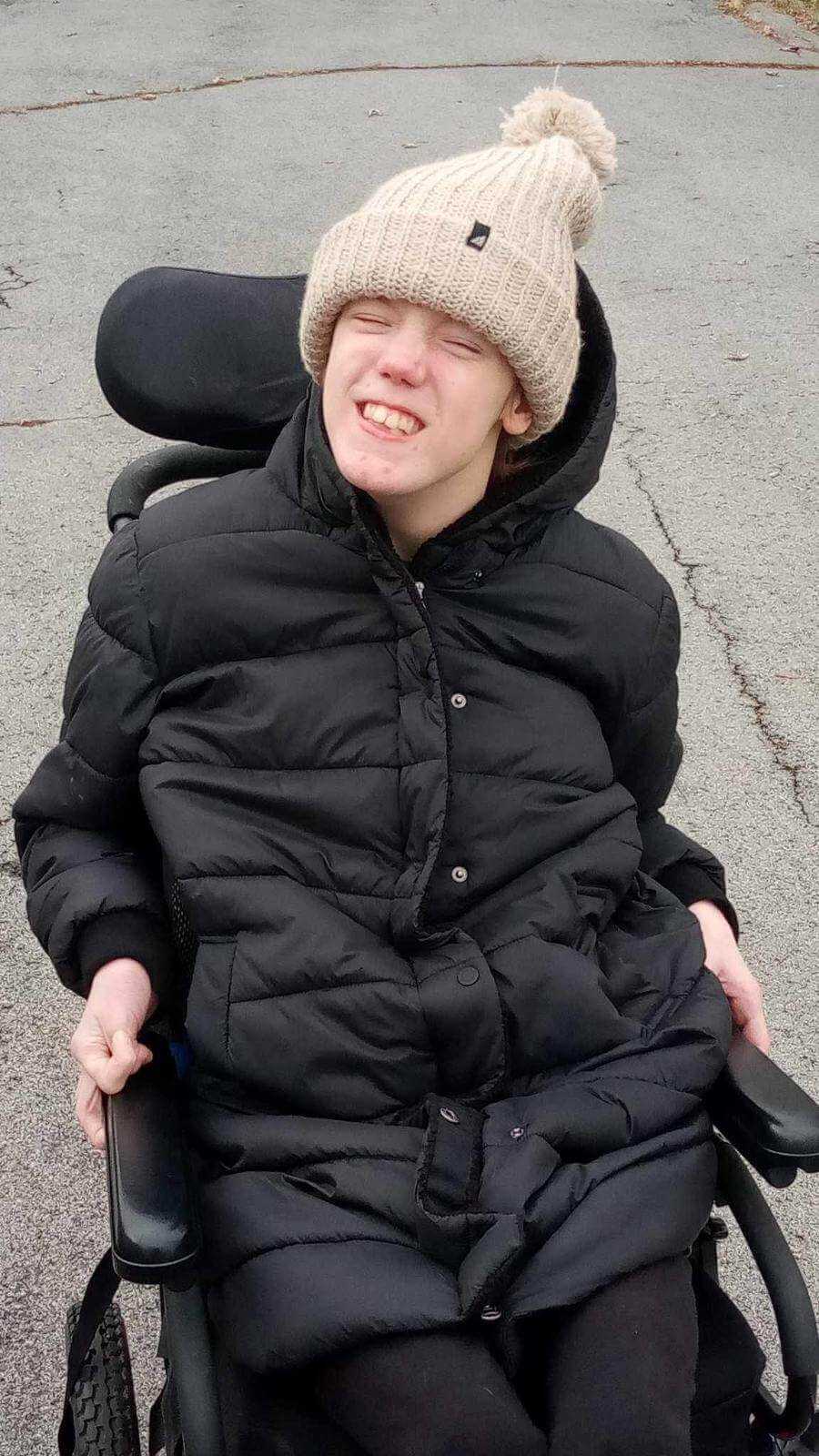 Adult Acrylic Ribbed Cuff Hat with Matching Pom – Cozy & Classic worn by a young person in a wheelchair.