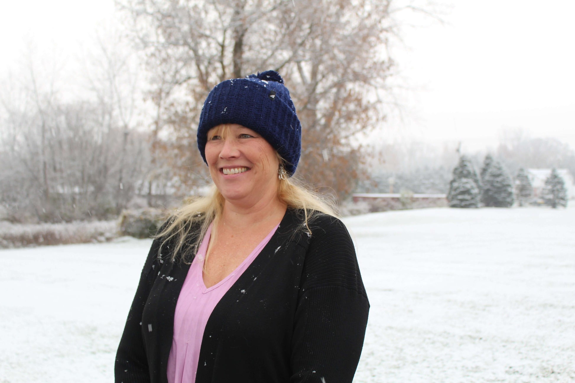 Adult Acrylic Ribbed Cuff Hat with Matching Pom – Cozy & Classic worn in snowy outdoor setting by a smiling woman.