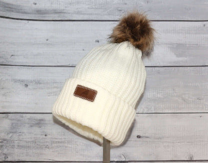 Adult Acrylic Ribbed Cuff with Pom Hat – Cozy, Classic, Giftable on display against a wooden background.