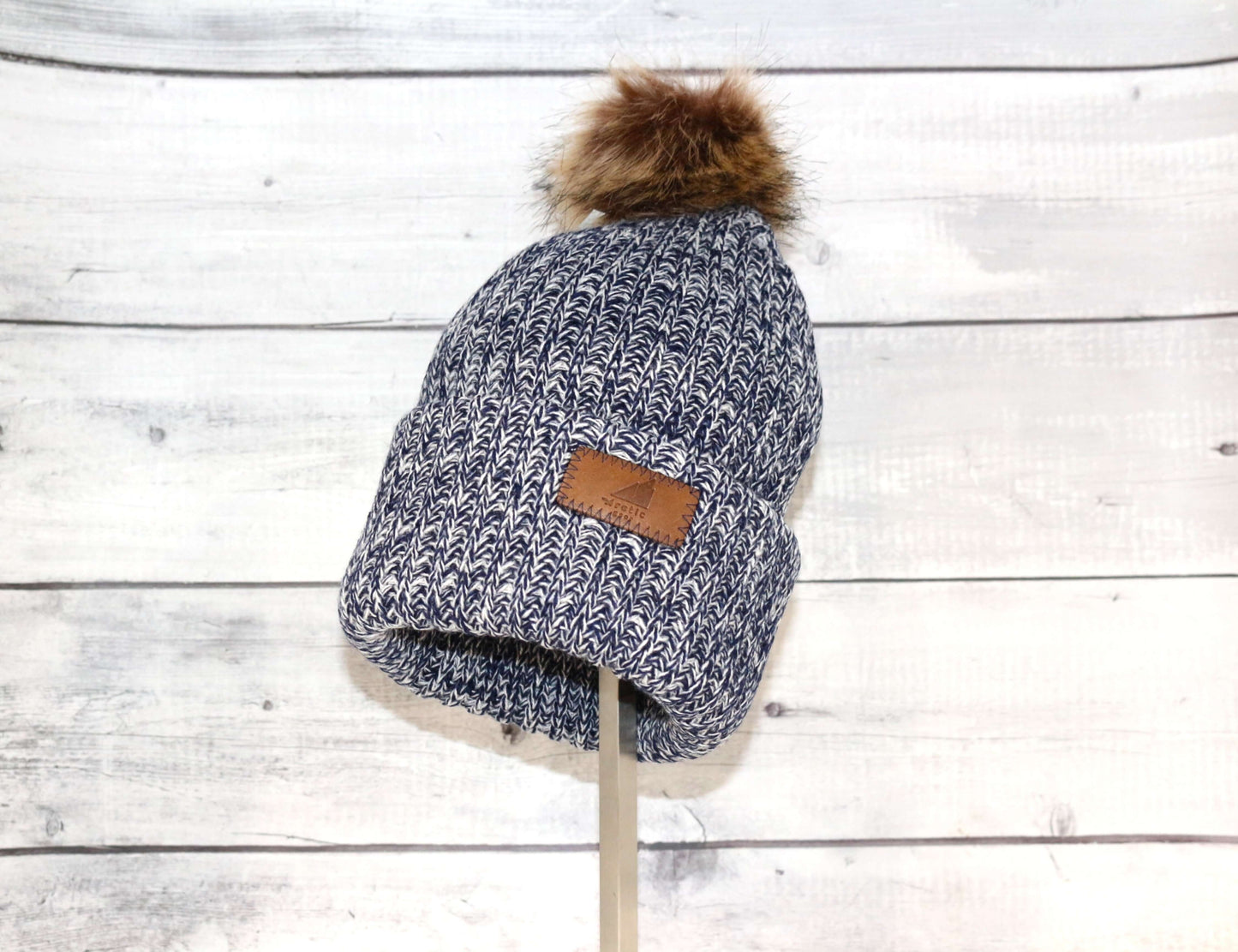 Adult Acrylic Ribbed Cuff with Pom Hat – Cozy, Classic, Giftable displayed against a rustic wooden background.