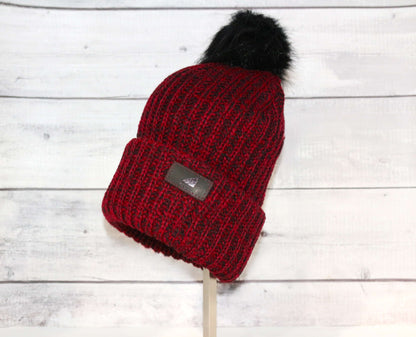 Adult Acrylic Ribbed Cuff with Pom Hat – Cozy, Classic, Giftable in red with black pom on a wooden display.