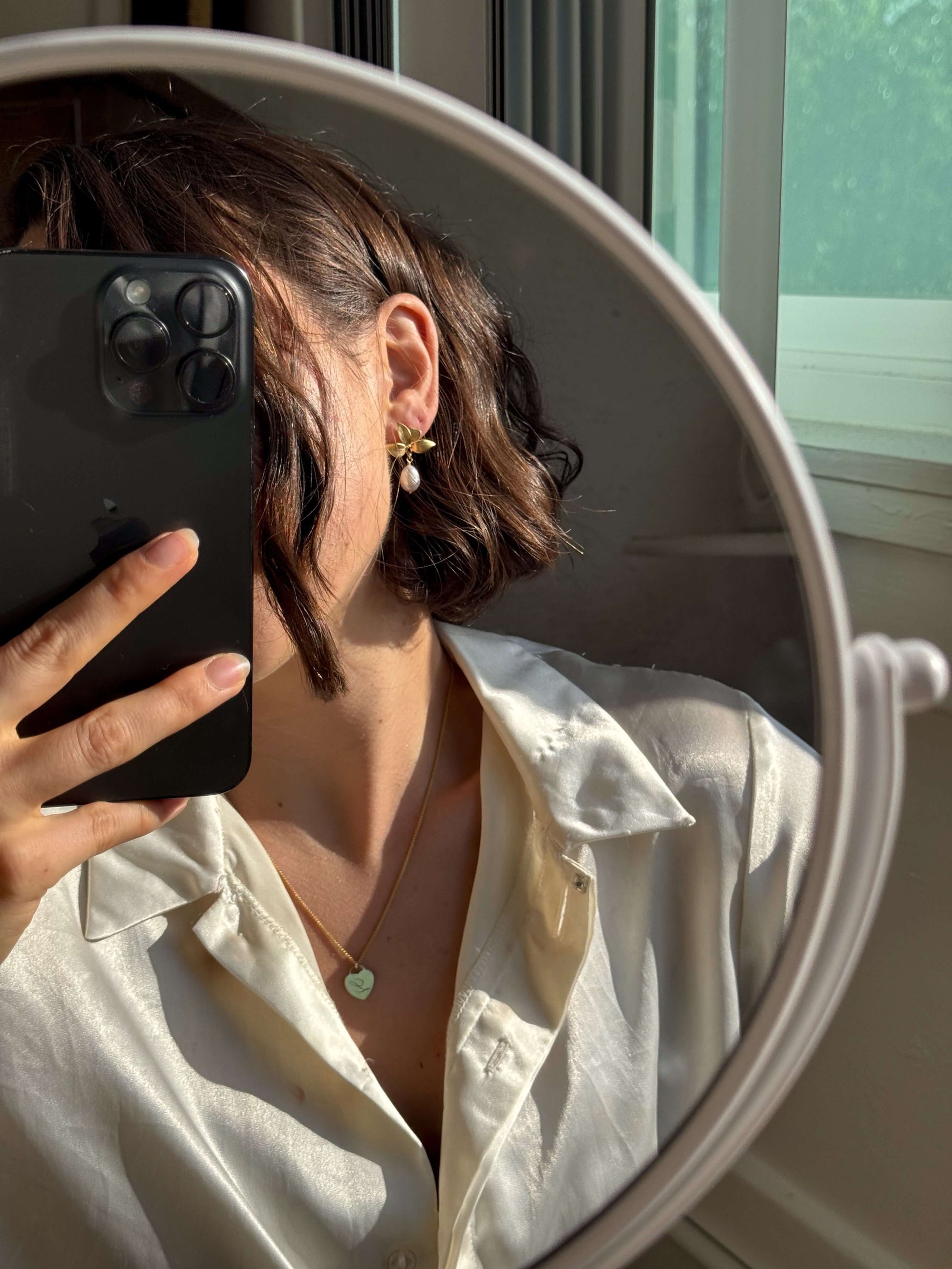 Woman wearing the Alice Initial Necklace – Personalized 14k Gold-Filled Heart, styled with a silk shirt and mirror reflection.