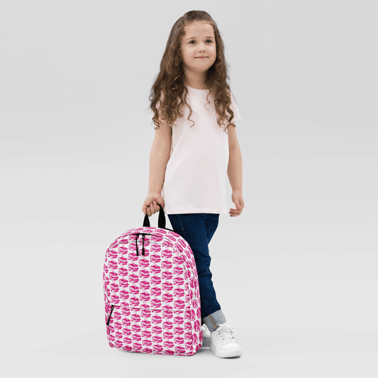 Child holding a stylish pink Pack & Play Backpack, perfect for school and sports, featuring a playful pattern.