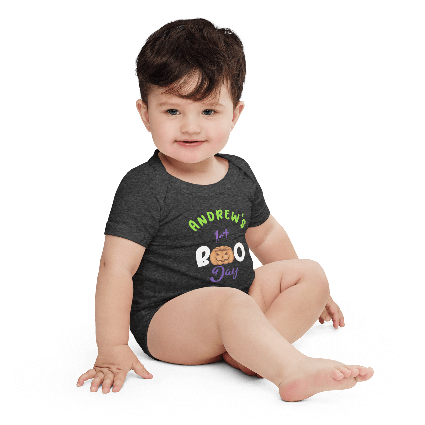 Baby in personalized black Halloween bodysuit with green and purple text, celebrating first Halloween with playful pumpkin design.