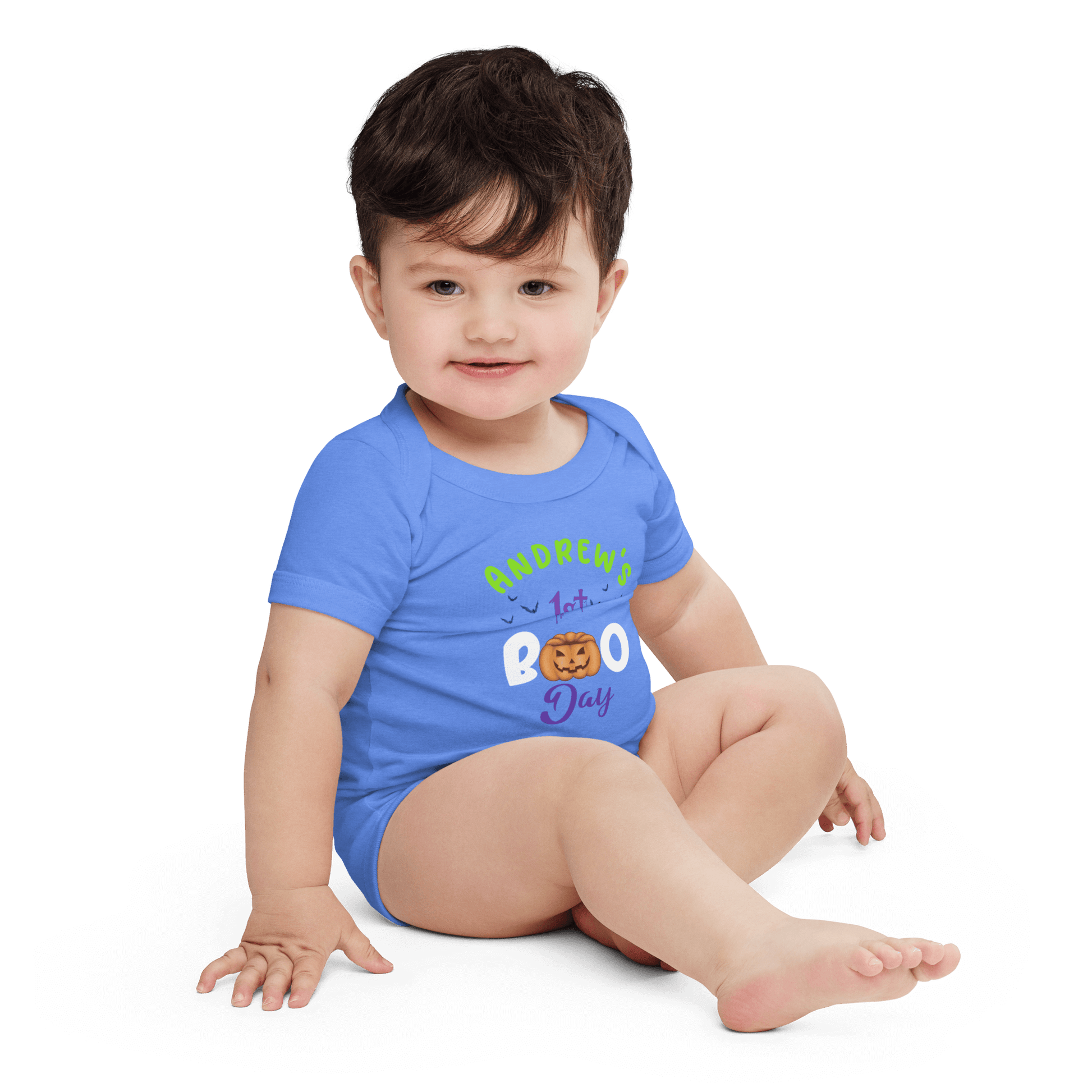 Baby in blue Halloween bodysuit with playful pumpkin design, celebrating 1st Boo Day.