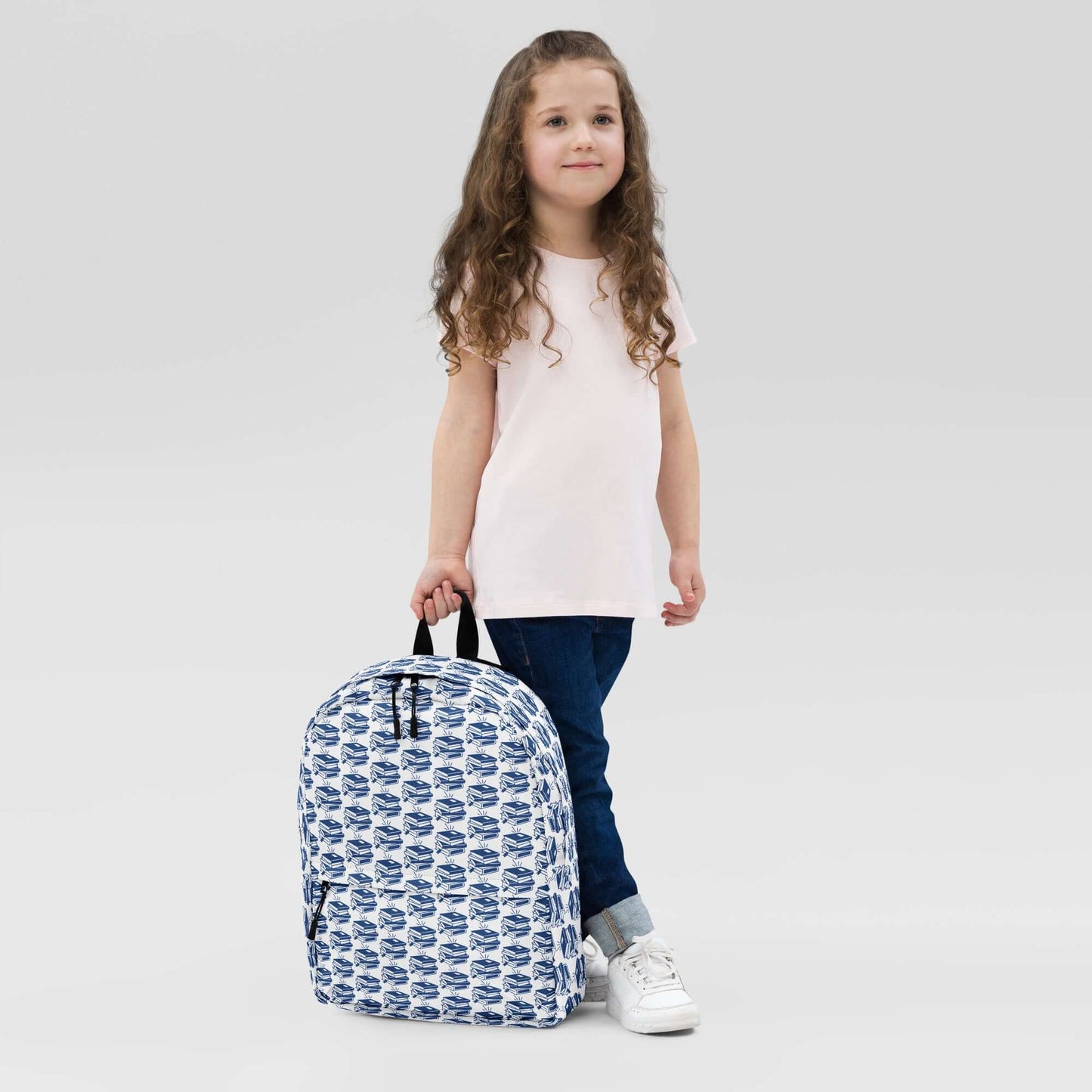 Child standing with The Bookish Backpack featuring a geometric book pattern, perfect for students and creatives.