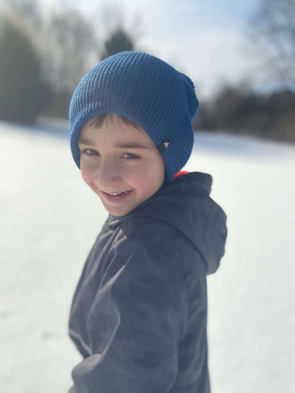 Child Acrylic Cuff Hat – Soft Knit Beanie for Kids worn by a smiling boy in a snowy landscape.