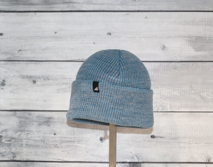 Child Acrylic Cuff Hat – Soft Knit Beanie for Kids displayed on a stand against a wood backdrop.