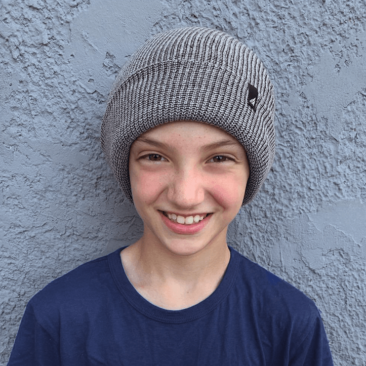 Child Acrylic Cuff Hat – Soft Knit Beanie for Kids worn by a smiling boy against a textured wall background.