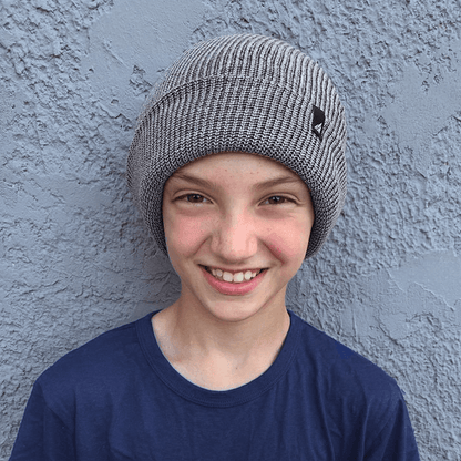 Child Acrylic Cuff Hat – Soft Knit Beanie for Kids worn by a smiling boy against a textured wall background.